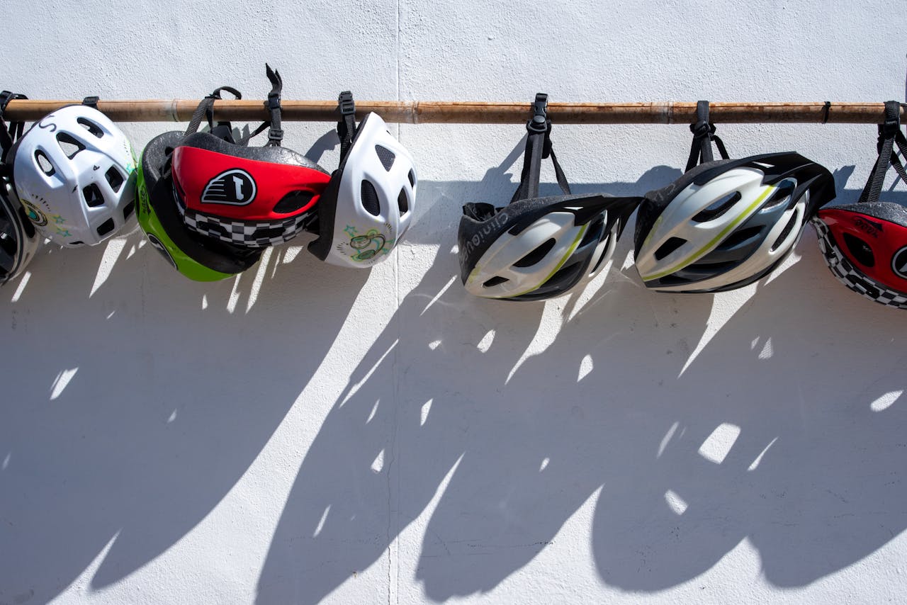 Services A row of colorful bike helmets hanging on a wall, casting shadows.